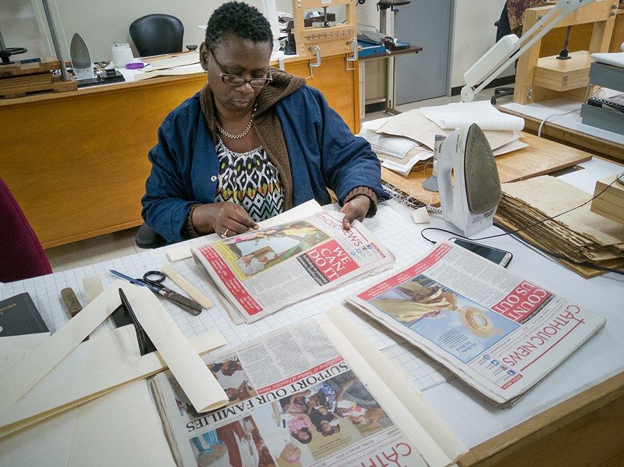 Janice Jeffrey of the Conservation Lab, National Archives,  prepares issues of the Catholic News for preservation. Photo by Mark Lyndersay.